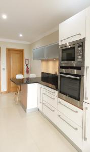 a kitchen with white cabinets and a microwave at Apartamento Íris in Lagos +11 photos