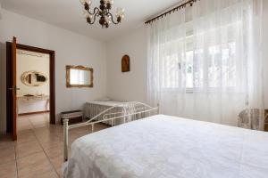 een witte slaapkamer met een bed en een raam bij Villetta delle Viole by BarbarHouse in Torre Ovo