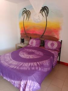 un letto viola in una stanza con un dipinto sul muro di Al Jannah a Somone