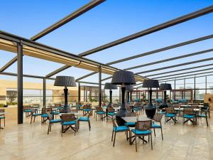 eine Cafeteria mit Tischen und Stühlen in einem Gebäude in der Unterkunft Fairmont Amman in Amman