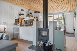 a kitchen with a stove in a living room at Charmerende sommerhus - 200 m fra stranden in Marielyst