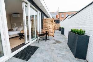 een patio met een tafel en stoelen op een balkon bij Hotel - B&B Renesse in Renesse