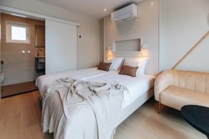 a bedroom with a large white bed and a chair at Hotel - B&B Renesse in Renesse