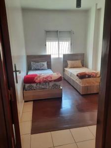 2 Betten in einem Zimmer mit einem Kreuz an der Wand in der Unterkunft Bel Appartement à louer in Agadir