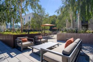 a patio with benches and tables and umbrellas at San Mateo 1br w pool gym wd nr Caltrain SFO-1237 in San Mateo