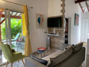 a living room with a couch and a tv at Location villa et piscine privé in Capesterre-Belle-Eau