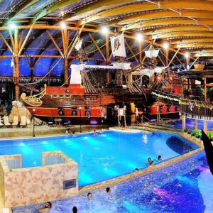 ein großes Schwimmbecken mit einem Piratenschiff im Hintergrund in der Unterkunft Holiday Resort Šefec in Liptovská Sielnica