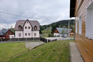 una gran casa blanca con una valla en una ciudad en Útulný horský apartmán v Jizerských horách, en Bedřichov