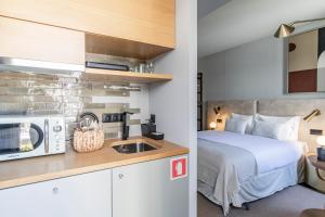 a bedroom with a bed and a kitchen with a microwave at Regras 45 Building B by LovelyStay in Porto