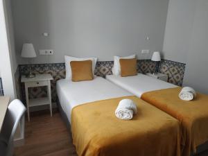 two beds in a hotel room with towels on them at Great Stay Fanqueiros Guest House 3 in Lisbon