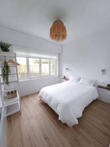 ein weißes Schlafzimmer mit einem großen Bett und einem Fenster in der Unterkunft Casa Maruxa in A Coruña