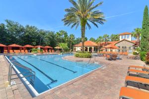 einen Pool in einem Resort mit Stühlen und einer Palme in der Unterkunft Near Disney w/ pool-3BR/2BA-Spacious & Cozy Condo in Davenport