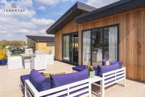 a patio with purple cushions and white chairs at Waterfront Lodge Windsor Racecourse Marina in Windsor