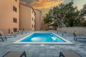 a swimming pool in a courtyard with chairs and a building at Apartments Cesare with Shared Pool in Ližnjan