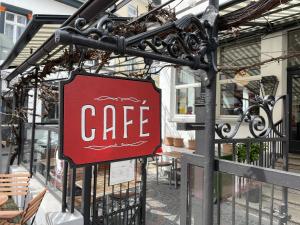 un panneau de café rouge sur le côté d'un bâtiment dans l'établissement Storyhotel Bergischer Hof Königswinter, à Königswinter