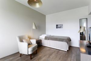 a white bedroom with a bed and a chair at Forenom Serviced Apartments Helsinki Lapinlahdenkatu in Helsinki