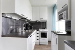 a kitchen with white cabinets and a sink at Forenom Serviced Apartments Helsinki Lapinlahdenkatu in Helsinki
