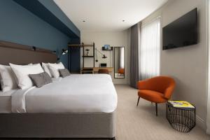 - une chambre avec un grand lit et une chaise dans l'établissement 55 by Le Mirage, à Londres