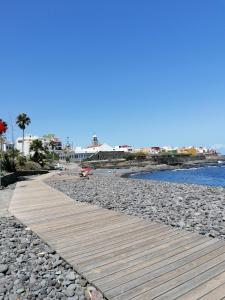 a wooden walkway on a rocky beach with the ocean at Casa Ela in Caleta de Interián