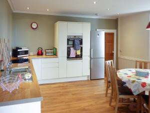 a kitchen with a table and a white refrigerator at Kirkbride Farmhouse - 28471 in Creetown