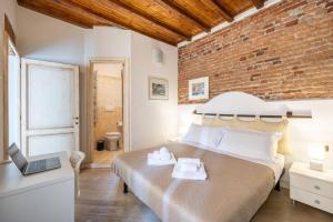 ein Schlafzimmer mit einem Bett und einer Ziegelwand in der Unterkunft [TICINESE-DUOMO ELEGANTE] Centrale con A/C in Mailand