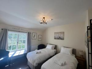 two beds in a room with a window at The New Forest Inn in Lyndhurst