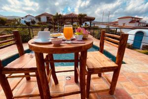 a wooden table with two chairs and orange juice at Hermoso Glamping Milos in Barichara