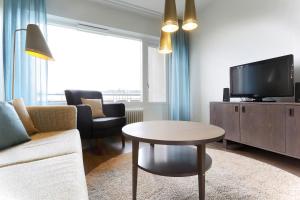 - un salon avec un canapé, une télévision et une table dans l'établissement Forenom Serviced Apartments Helsinki Lapinlahdenkatu, à Helsinki