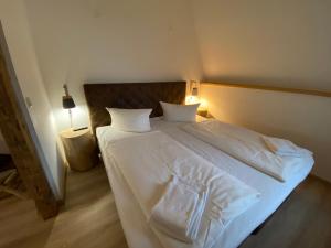 uma cama com lençóis brancos e almofadas num quarto em Fasa Lodge em Kurort Oberwiesenthal