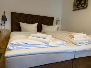 uma cama com lençóis brancos e toalhas em Fasa Lodge em Kurort Oberwiesenthal