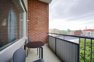 balcón con mesa, sillas y pared de ladrillo en Forenom Serviced Apartments Helsinki Lapinlahdenkatu, en Helsinki