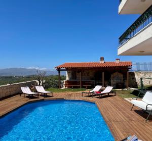 una piscina en una terraza con sillas y una casa en Olive Villa, en Xirokámbion