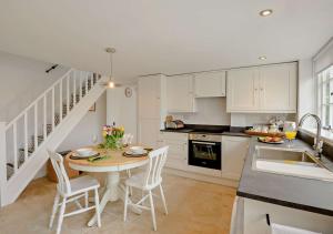 una cucina con armadi bianchi, tavolo e sedie di Chantry Place a Long Melford