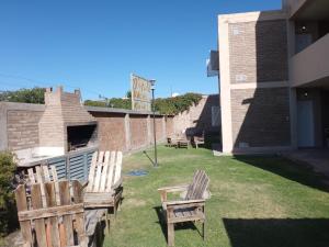 two wooden chairs sitting on the grass in a yard at Complejo La Carlota in San Juan