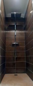 a bathroom with a shower with brown tiles at Le 4 in Montignac