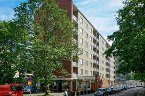 a building on a city street with cars parked next to it at Forenom Serviced Apartments Helsinki Lapinlahdenkatu in Helsinki