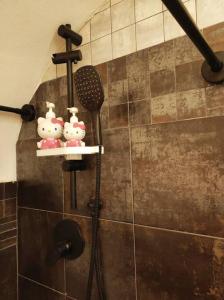 una ducha con tres figuritas de hola gatito en un estante en La tana di Topolino, en Imola