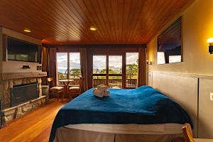 a bedroom with a blue bed and a fireplace at Surya-Pan Hotel Refúgio in Campos do Jordão