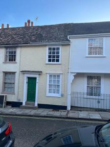 a white house with a green door on a street at Historic Town Centre Cottage in Bury Saint Edmunds
