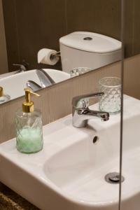 a bathroom sink with a bottle of soap and a mirror at Sunset Retreat 1a linha de mar in Monte Gordo