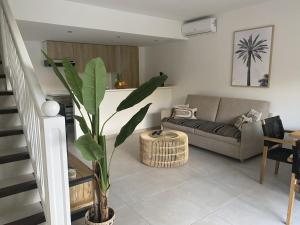 ein Wohnzimmer mit einem Sofa und einer Pflanze in der Unterkunft Cottage Cosy Duplex Anse Marcel, Vue mer et marina in Anse Marcel 