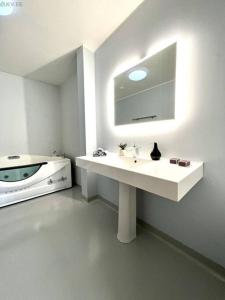 La salle de bains blanche est pourvue d'un lavabo et d'un miroir. dans l'établissement Rentida luxuslik maja., à Tallinn