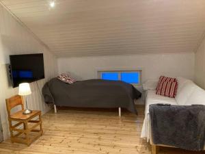 a bedroom with a bed and a couch and a tv at Trevlig stuga/gårdshus med egen parkering in Burträsk