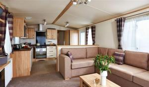 a living room with a couch and a kitchen at Hoburne Devon Bay Stunning 3 bed static caravan with full decking in Paignton