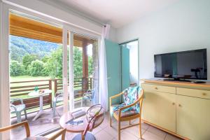 a living room with a television and a balcony at Village Club Les Balcons des Pyrénées in Saint-Mamet