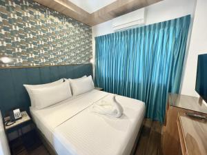 Lighthouse Point Hotel في دوماغيتي: غرفة بسرير عليها طير ابيض