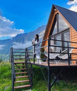 a woman standing on the deck of a tiny house at Kazbegi Kuro Cottages in Kazbegi