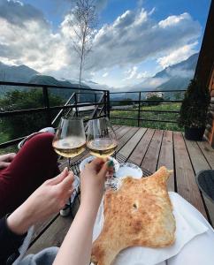 dos personas sentadas en una mesa con dos copas de vino en Kazbegi Kuro Cottages en Kazbegi