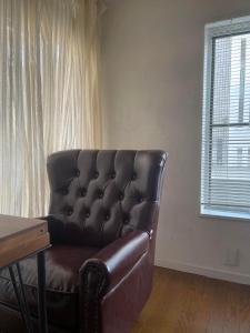 a leather couch in a living room with a window at 経堂の小さな一棟貸wakusei in Tokyo