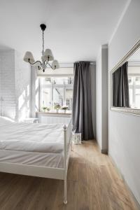 a white bedroom with a bed and a window at Too-Good Apartments in Krakow